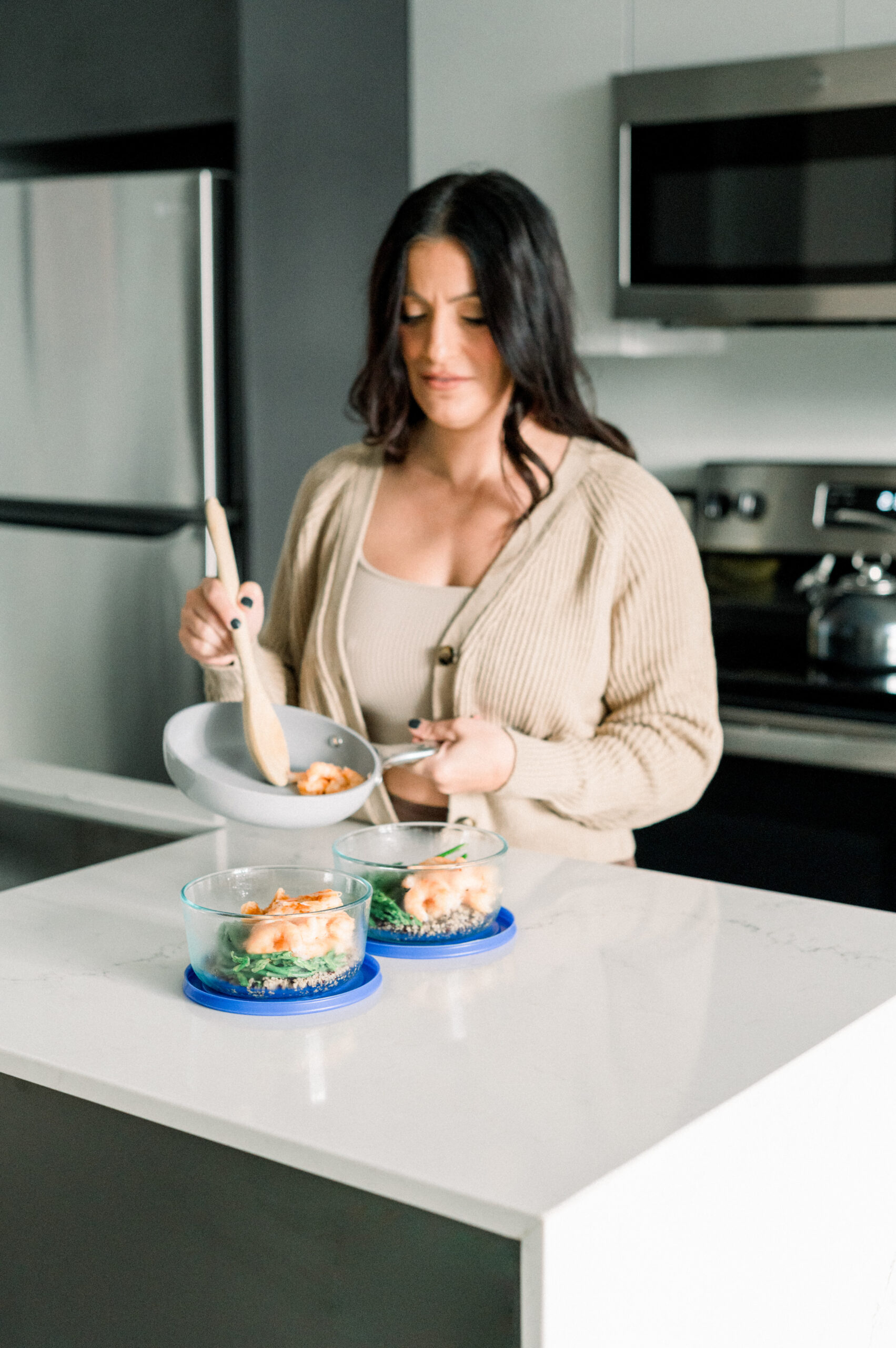 women in kitchen putting food into meal prep containers