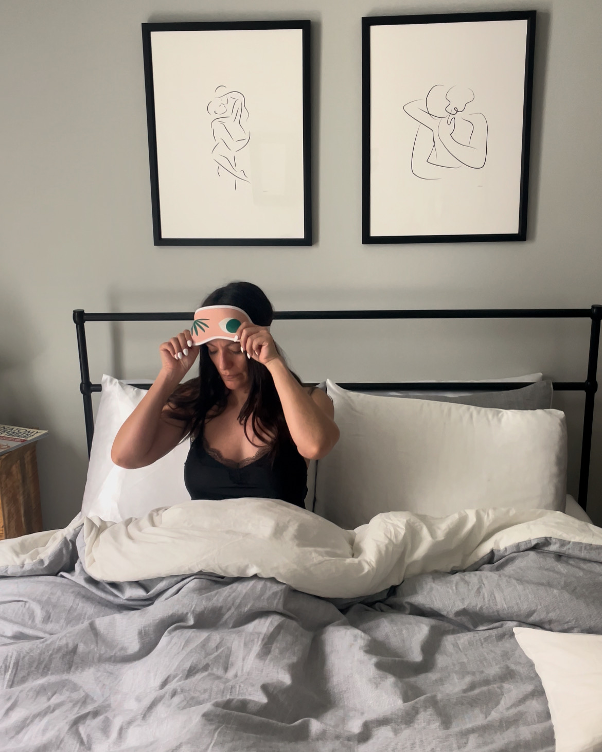 women in bed putting sleep mask on