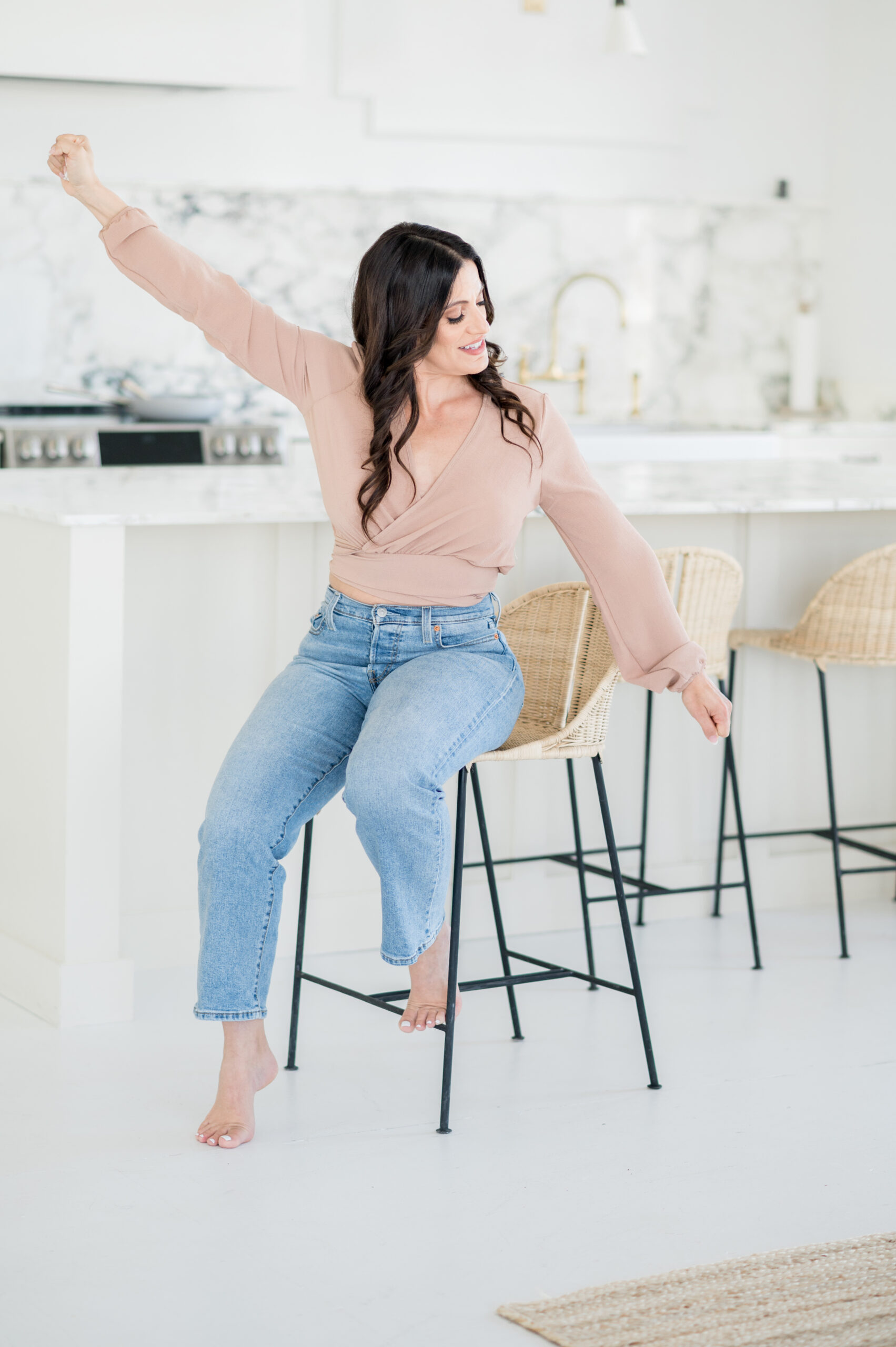 woman on kitchen stool with arms extended, excited look on her face