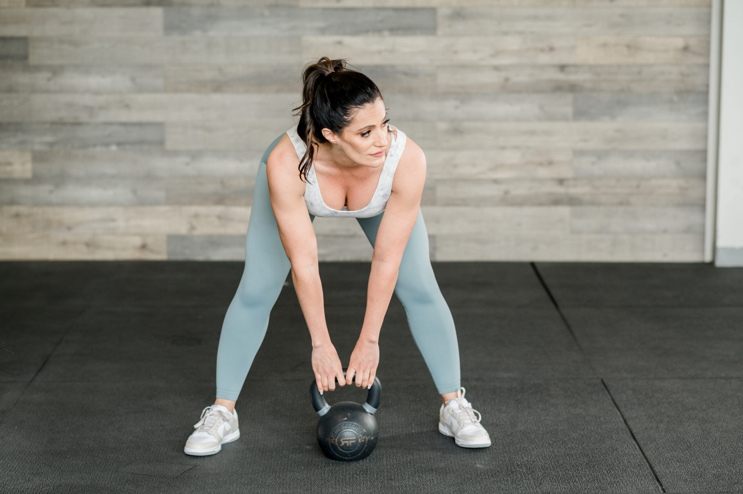 woman in gym holding kettle bell in wide stance
