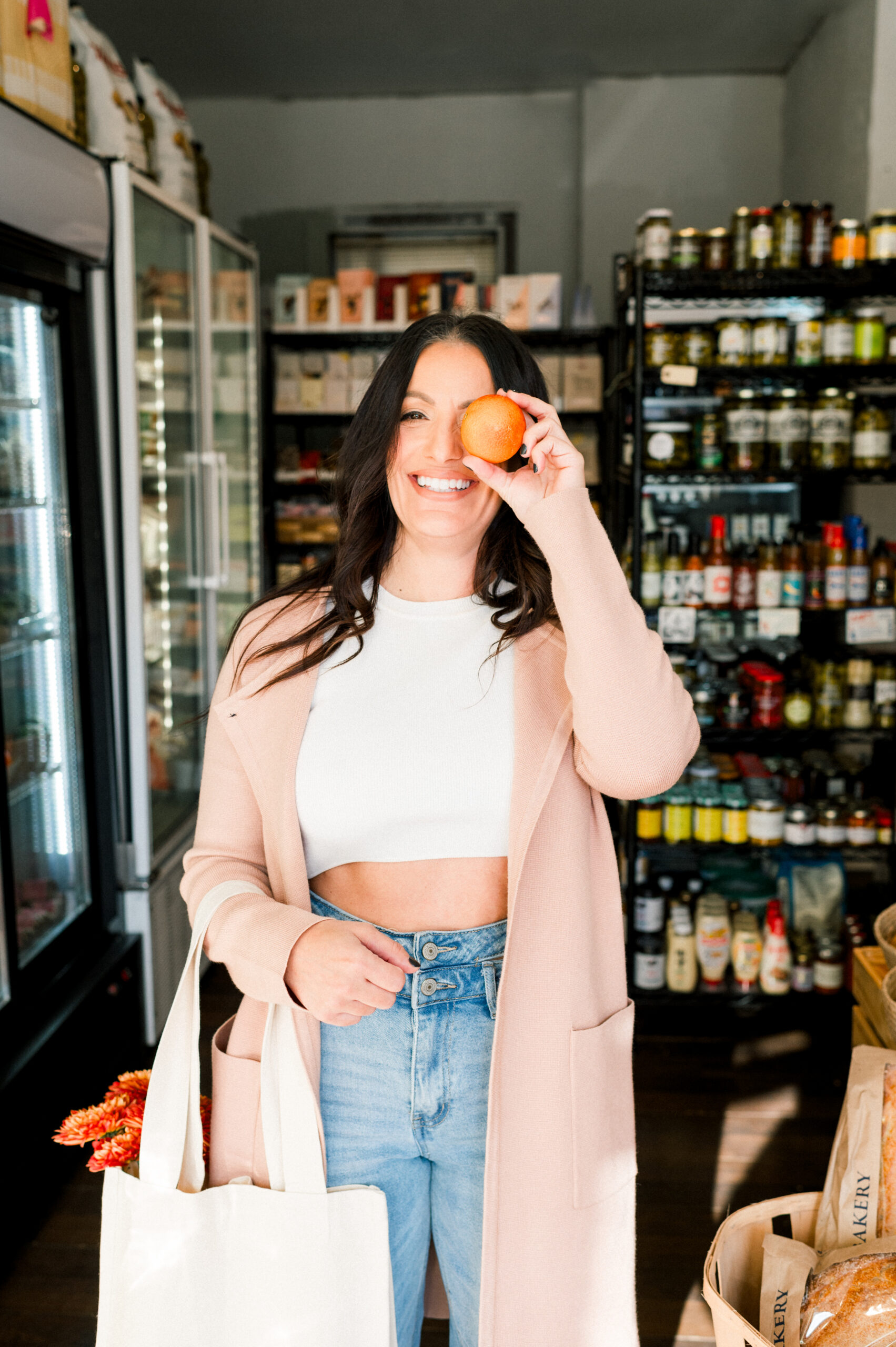 girl at store holding an orange over her eye